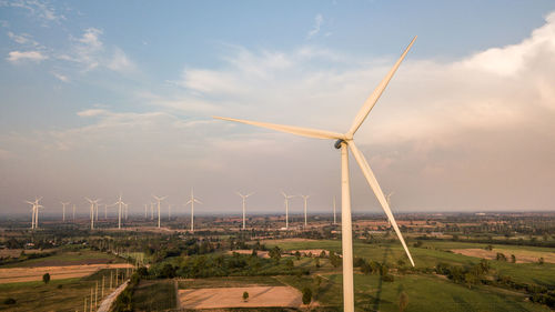 Scenic view of windmills on field against sky