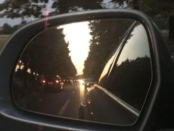 Vehicles on road seen through side-view mirror of car