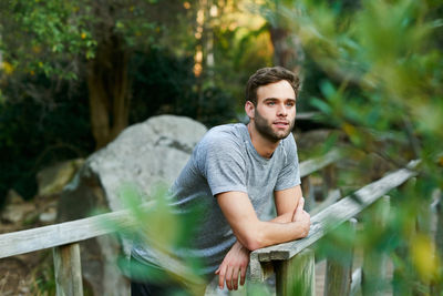 Portrait of young man standing against trees