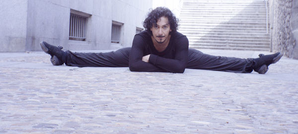 Portrait of man stretching legs on footpath