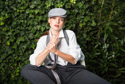 Portrait of confident woman clenching fist while sitting at backyard