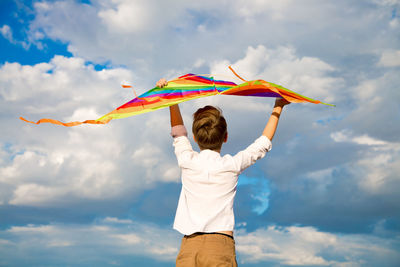 Rear view of woman holding umbrella against sky