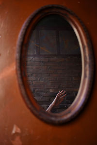 Reflection of hand on mirror against wall