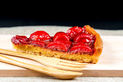Close-up of strawberry tart slice on wooden cutting board