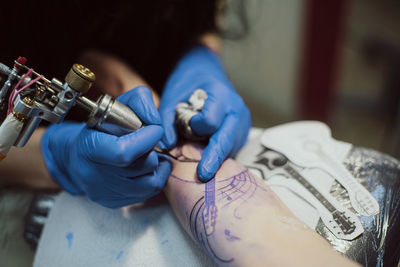 Midsection of artist making tattoo on customer hand