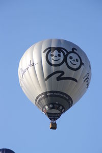 Low angle view of hot air balloon flying against clear blue sky