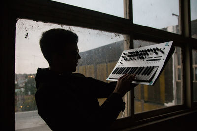 Side view portrait of silhouette man holding window