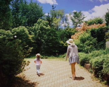 Rear view of mother and daughter walking in park