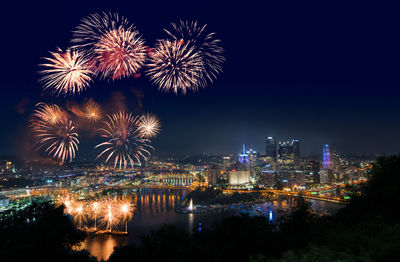 Firework display over illuminated buildings in city at night