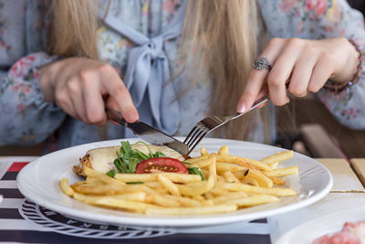 Midsection of woman eating food at table