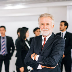 Portrait of businessman with colleagues standing in office