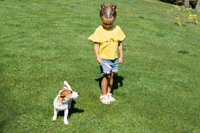 Portrait of boy playing with dog on grassy field