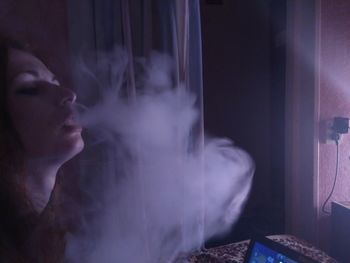 Close-up of woman smoking at home