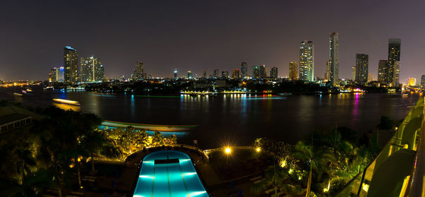 High angle view of illuminated swimming pool and river in city at night