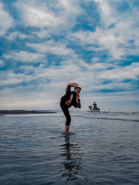 Full length of woman standing in sea against sky