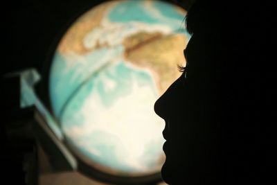 Close-up of silhouette man against illuminated light at night