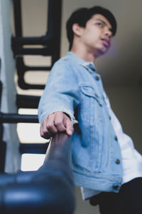 Low angle view of young man standing by railing