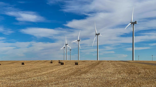 Wind turbines on field against sky