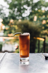 Tamarind whiskey sour in tall collins glass with lime wedge