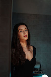 Portrait of beautiful young woman leaning on wall