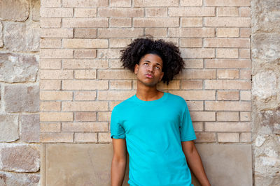 Young man standing against brick wall