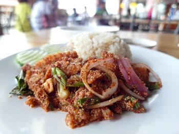 Close-up of spicy chicken and rice on plate at restaurant