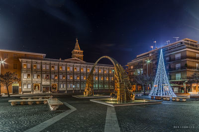 Illuminated buildings against sky at night