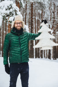 Portrait of smiling man standing on snow covered land