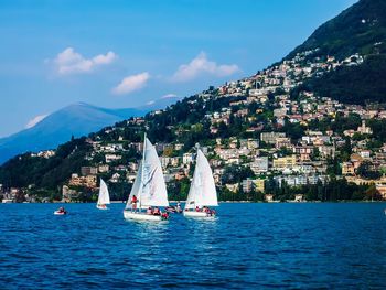 Sailboat sailing on sea by mountain against sky