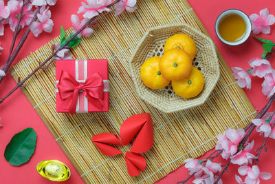 High angle view of flowers with oranges and craft products over red background