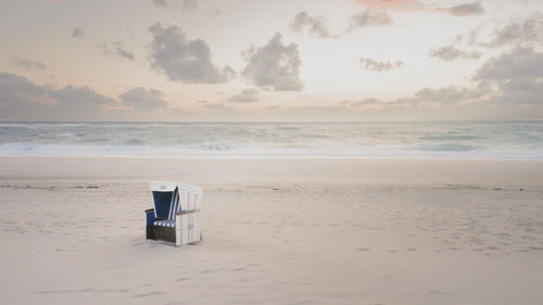 Hooded beach chair on sandy beach at sunset