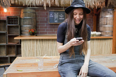 Portrait of smiling young woman using mobile phone at table