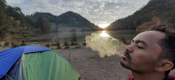 Portrait of young man in mountains against sky