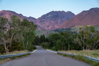 Road amidst trees and mountains against sky