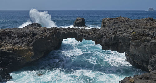 Waves splashing on shore against sky