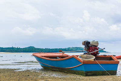 Boat moored on beach against sky