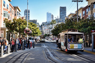 People on street in city against clear sky with tramway in san francisco