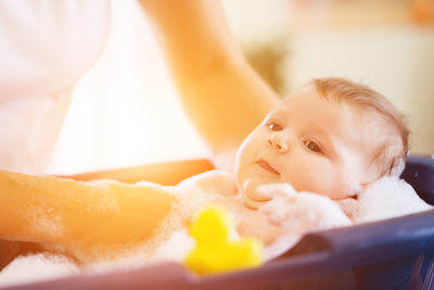 Midsection of mother bathing daughter in baby tub