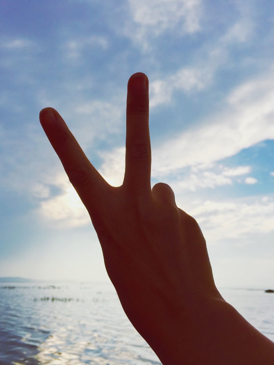 sky, person, sea, part of, water, cloud - sky, horizon over water, beach, cloud, cropped, beauty in nature, nature, human finger, personal perspective, focus on foreground, holding, unrecognizable person