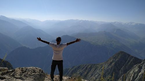 Rear view of man standing on mountain against sky