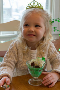 Cute girl with ice cream on table at home