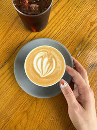 Cropped image of hand holding coffee on table