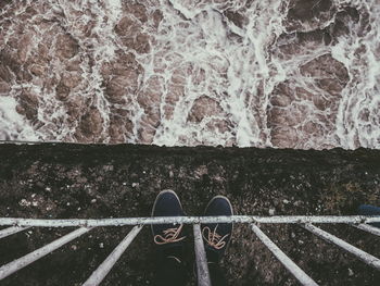 Low section of person standing by railing against sea