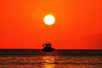 Silhouette boat in sea against clear sky during sunset