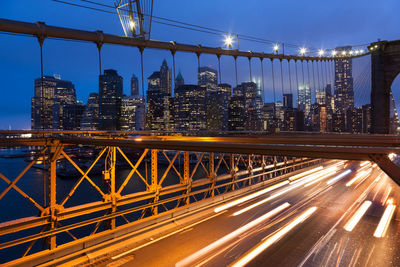 Illuminated bridge in city against sky at night