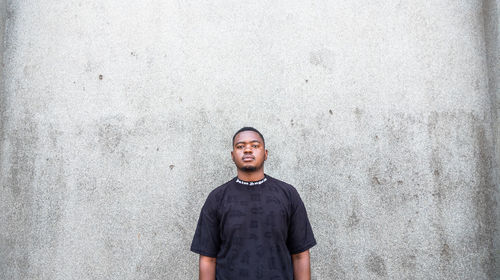 Portrait of young man standing against wall