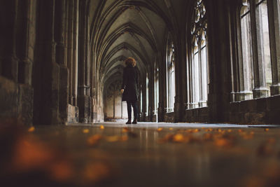 Low angle view of young woman standing at church corridor