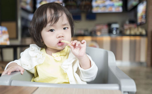 Close-up of cute baby girl eating french fries at restaurant