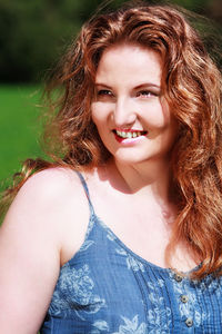 Smiling beautiful redhead woman looking away on sunny day