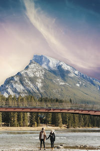 People standing by snowcapped mountain against sky